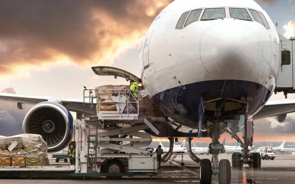 Cargo aircraft being loaded with freight on an airport tarmac at dusk