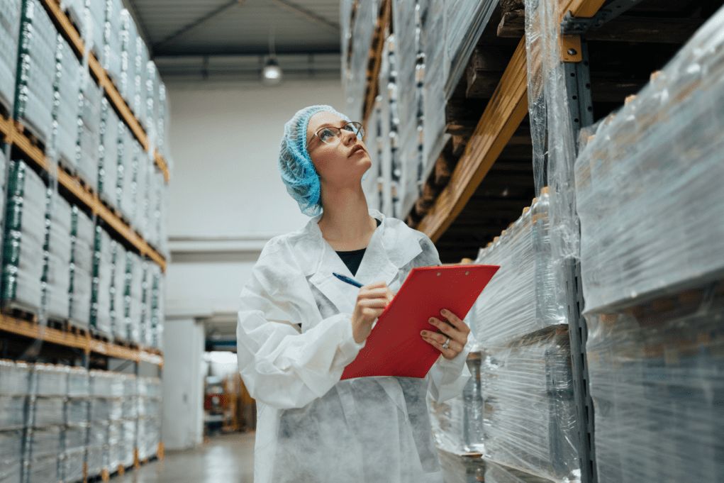 Logistics specialist in protective clothing checking stock levels of medical supplies in a distribution warehouse